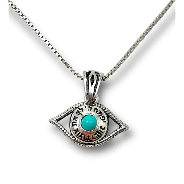 A silver pendant in the design of an eye, with the blessing "May the Lord open His good treasure" embedded with a turquoise stone.